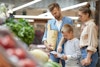 a man and woman looking at a paper and a child looking at a grocery
