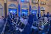 a group of people sitting in chairs in a room with blue lights