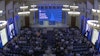 a group of people sitting in chairs in a room with a stage and a screen