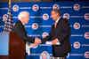 two men shaking hands in front of a podium