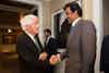 a man in suits shaking hands with another man in a room