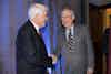 two men shaking hands in front of curtains